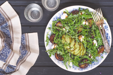 Arugula salad with goat cheese and avocado with plums  