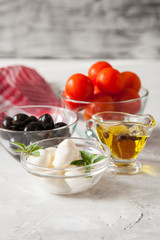 ingredients for salad - cheese, a tomato, olives and oil. selective focus