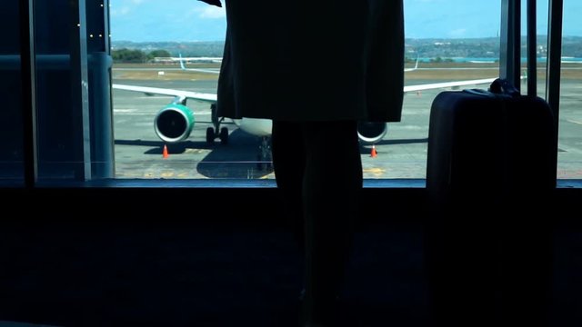Woman with luggage walking towards window at airport, super slow motion 240fps
