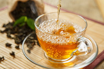 Cup of tea and leaves tea on wooden placemat