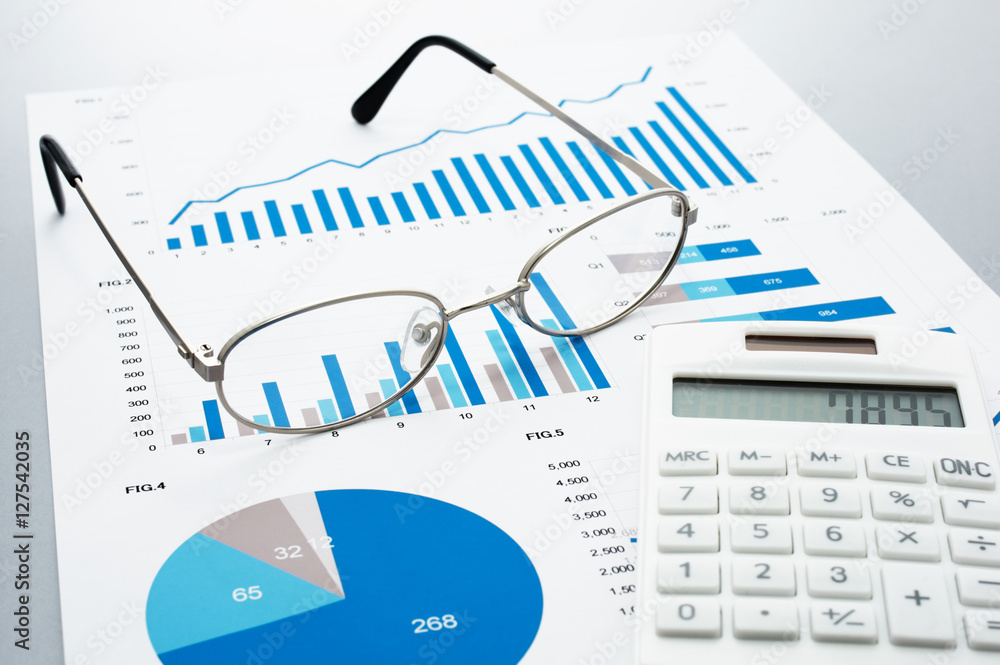 Poster Business document, glasses, and calculator on gray reflection background.
Many graphs and charts. Concept image of data reviewing.
