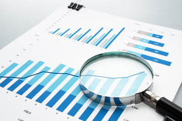 Reviewing business report. Looking at growth chart with magnifying glass.
Document, charts and...