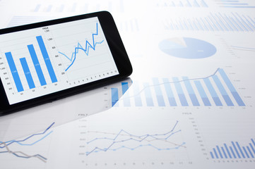 Business data, charts and smartphone. Many charts and graphs. Reflection light and flare.
