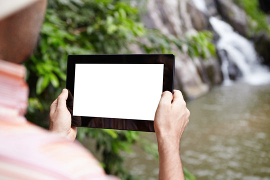 Caucasian scientist or ecologist recording video of wildlife and mountain river in nature reserve, using digital tablet with white blank copy space screen for your advertising content. View from back