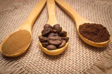 Grains, ground and instant coffee with wooden spoon on jute canvas