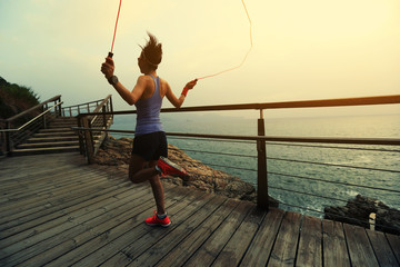 young fitness woman skipping rope at seaside - obrazy, fototapety, plakaty