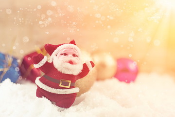 Small Santa Claus and Christmas decoration on white snow with ra