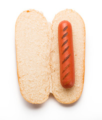 Hot dog bun with grilled sausage isolated on white background. Top view.