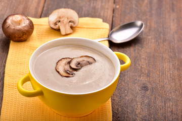 Mushroom cream soup on yellow napkin. Wooden table. Copyspace.