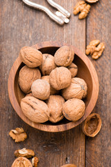 Walnuts in wooden bowl on table with Nutcracker. Top view.