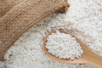 Organic white rice in wooden spoon and hemp sack, glutinous rice