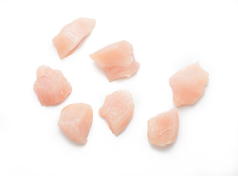 Raw chicken fillet. Small pieces of meat isolated on white. Top view.