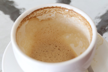 White coffee mug with coffee stains on table.