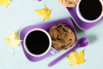 Colourful fall leaves and Purple coffee cup with saucer, spoon on light blue background