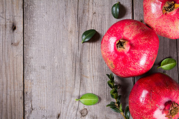 Some whole red pomegranate on rustic wooden unpainted table