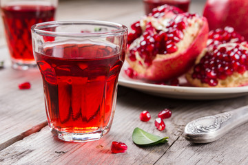 Whole and broken red ripe juicy pomegranates on rustic wooden unpainted table