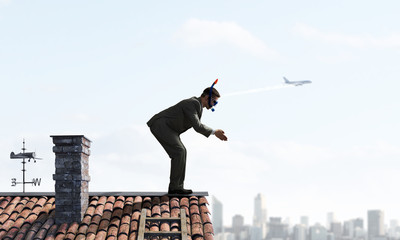 Businessman diving from roof . Mixed media