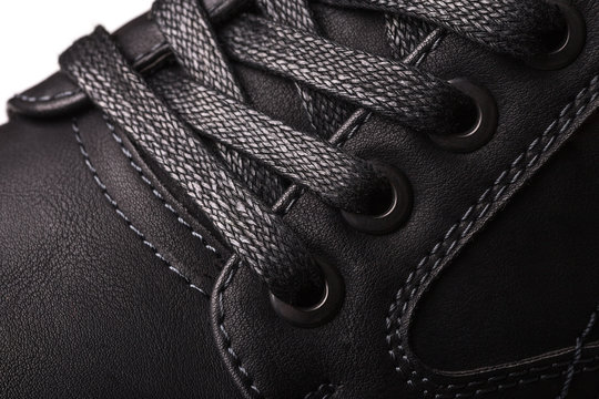 Macro picture of a part of a black men's boot. In the photo a part with loops for laces.