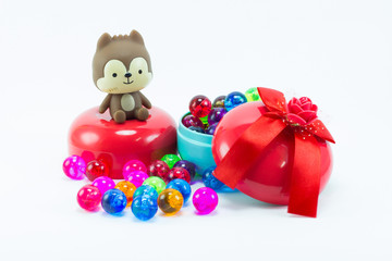 Teddy bear on red blue gift box and color plastic balls on  whit