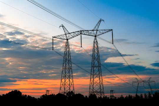 Electrical pylons on the background of the transformer substation during sunset.