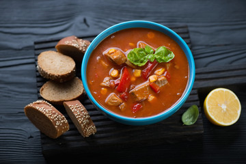 Tilapia chowder in a blue bowl over black wooden surface