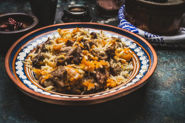 Rice with meat and vegetables in rustic plate on dark wooden table. Pilaf, national dish