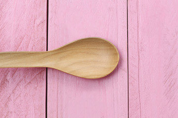 Wooden spoon on pink wood floors.