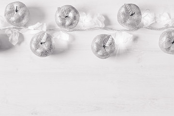 Obraz na płótnie Canvas Christmas silver apples decoration and burning lights on wooden white background. Xmas background.