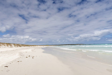 Water Washing Up On The White Sand with A View Of An Island 