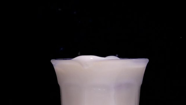 Cookie falling in glass of milk with splash in slow motion