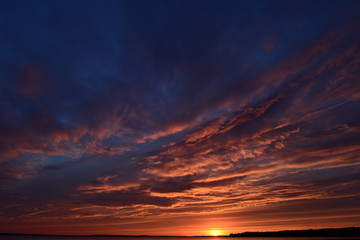 Blue cloudy sky in the light of the sunset over the lake