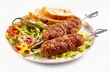 Long adana kebabs served with fresh salad