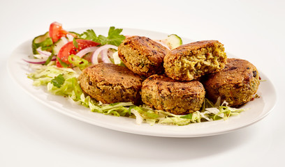Spicy fried felafel patties beside cut vegetables