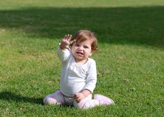 Smiling baby girl sitting on a grass