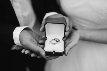 The bride and groom holding an open box with rings, a black and white image