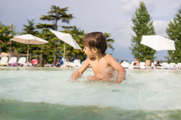 Young boy kid child splashing in swimming pool having fun leisur