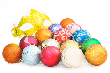 heap of colorful christmas baubles and carnival mask on white ba