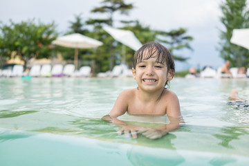 Young boy kid child splashing in swimming pool having fun leisur