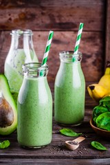 healthy green smoothie with banana, spinach, avocado  and chia seeds in glass bottles