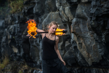 Girl in a black suit with flaming torches .