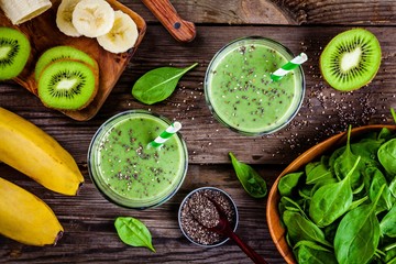 healthy green smoothie with banana, kiwi, spinach and chia seeds in glass jars