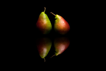 Two whole red and green pears isolated on black background