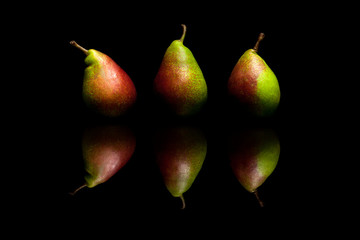 Three whole red and green pears isolated on black background