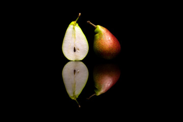 One cut in half and one whole red and green pears isolated on bl