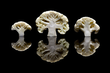 Cut in half three white cauliflowers isolated on black backgroun
