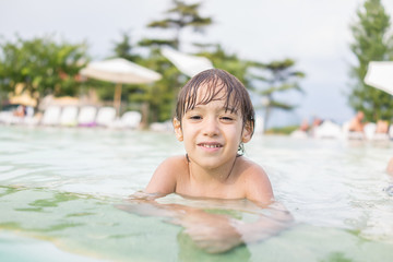 Young boy kid child splashing in swimming pool having fun leisur