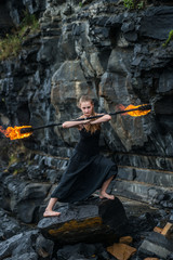 Girl in a black suit with flaming torches .