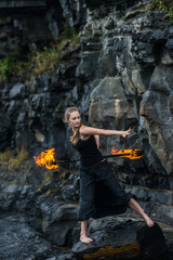 Girl in a black suit with flaming torches .
