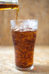 soft drink being poured into glass with ice
