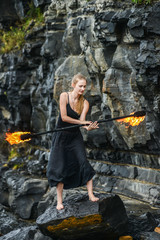 Girl in a black suit with flaming torches .